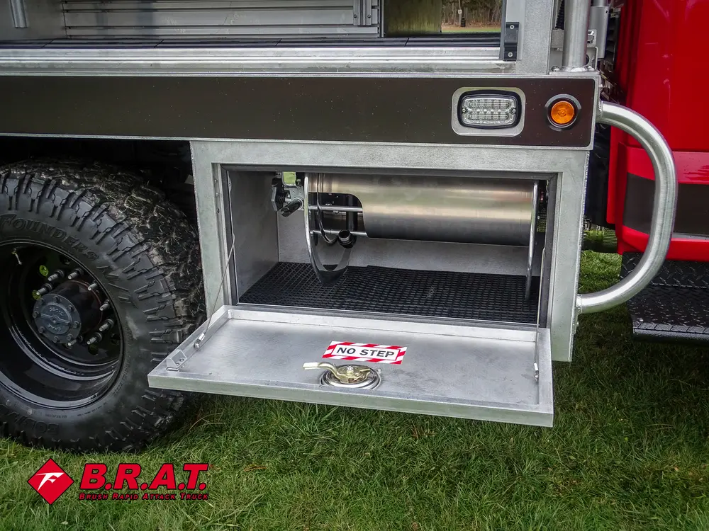 Exterior view of small fire truck showing cab, body compartments, and wheel/tire area.