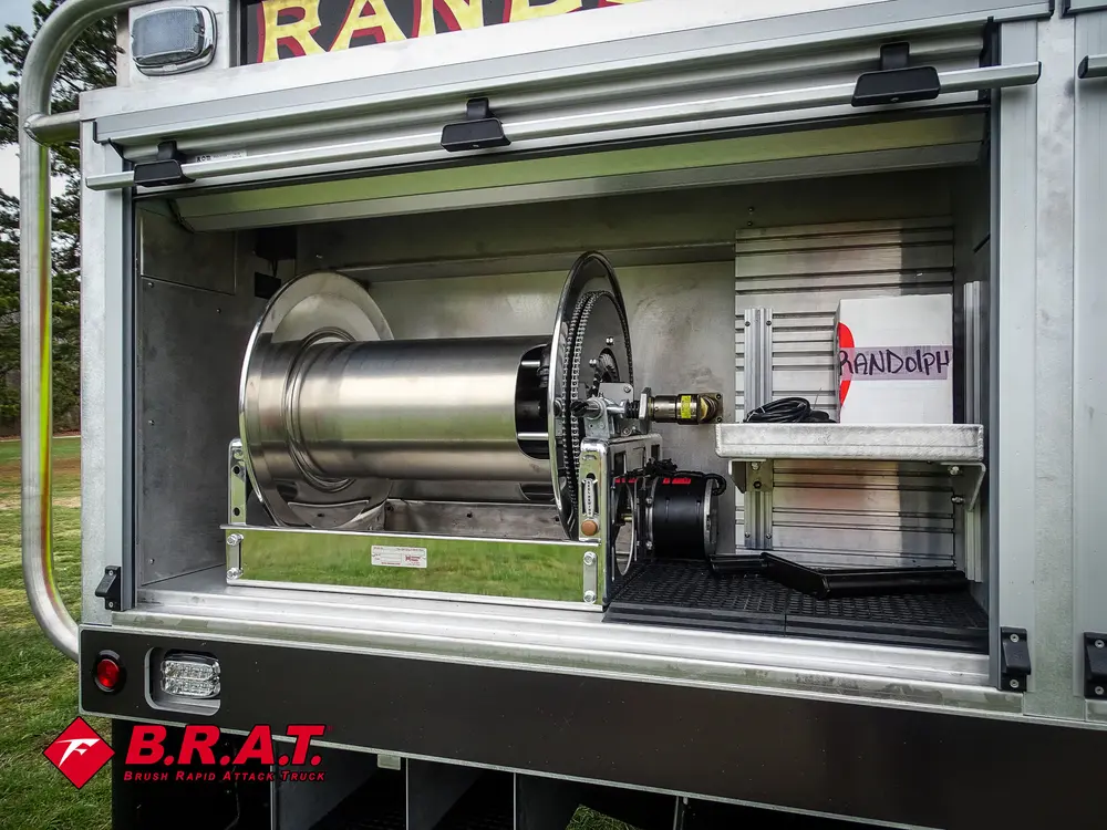 Exterior view of small fire truck showing cab, body compartments, and wheel/tire area.