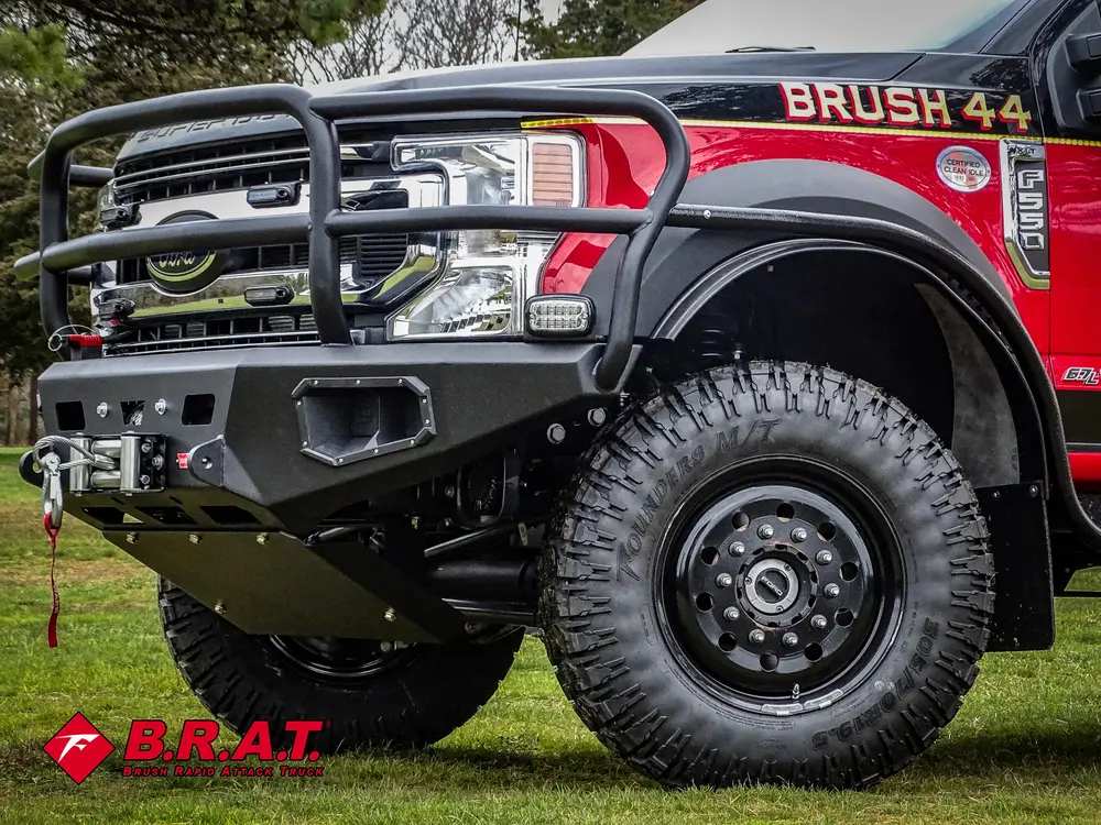 Exterior view of small fire truck showing cab, body compartments, and wheel/tire area.