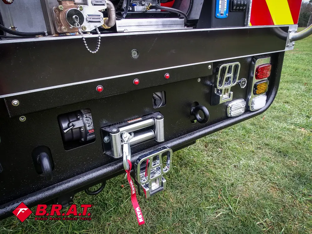 Exterior view of small fire truck showing cab, body compartments, and wheel/tire area.