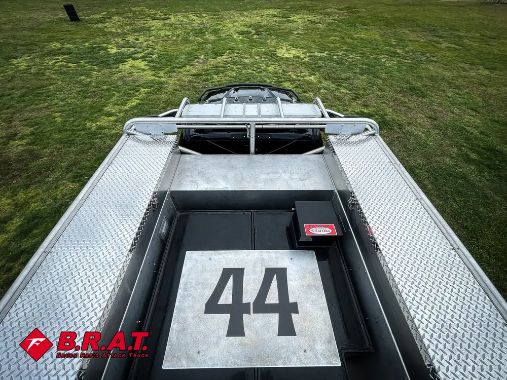Exterior view of small fire truck showing cab, body compartments, and wheel/tire area.