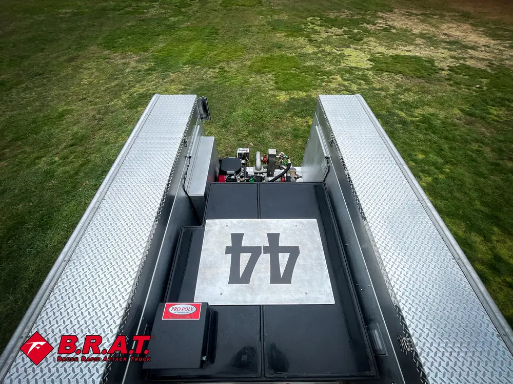 Exterior view of small fire truck showing cab, body compartments, and wheel/tire area.