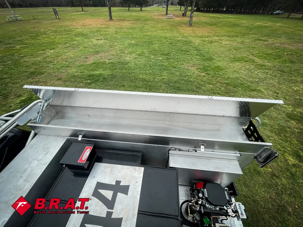 Exterior view of small fire truck showing cab, body compartments, and wheel/tire area.