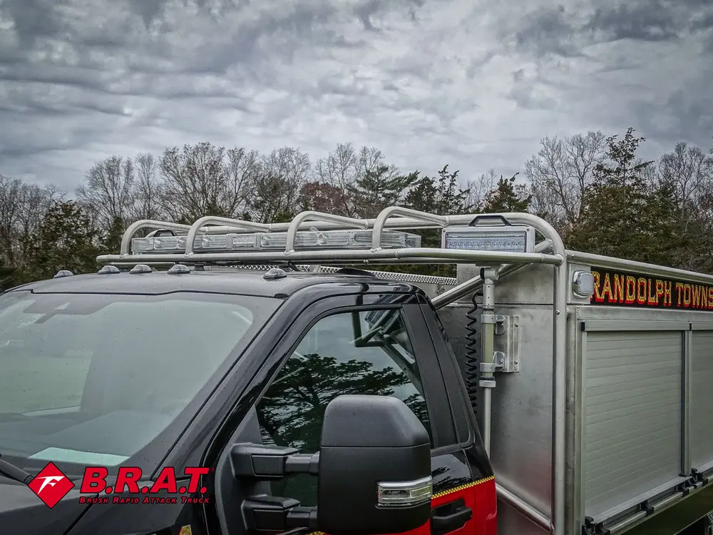 Exterior view of small fire truck showing cab, body compartments, and wheel/tire area.