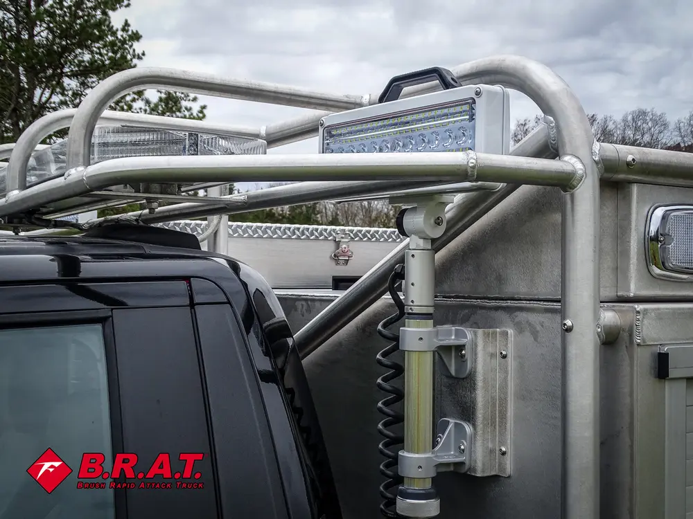 Exterior view of small fire truck showing cab, body compartments, and wheel/tire area.