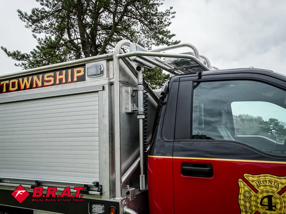 Exterior view of small fire truck showing cab, body compartments, and wheel/tire area.