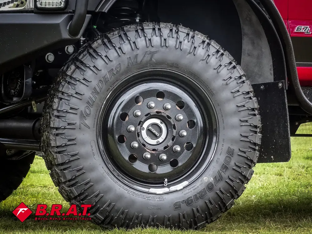 Exterior view of small fire truck showing cab, body compartments, and wheel/tire area.