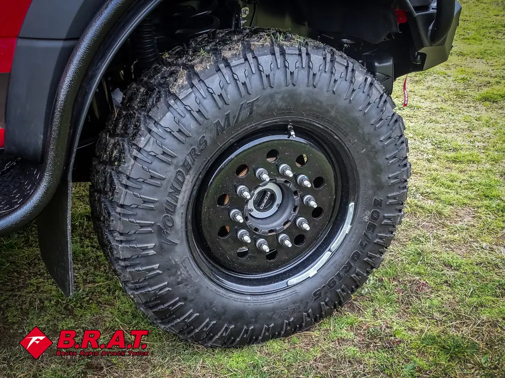 Exterior view of small fire truck showing cab, body compartments, and wheel/tire area.