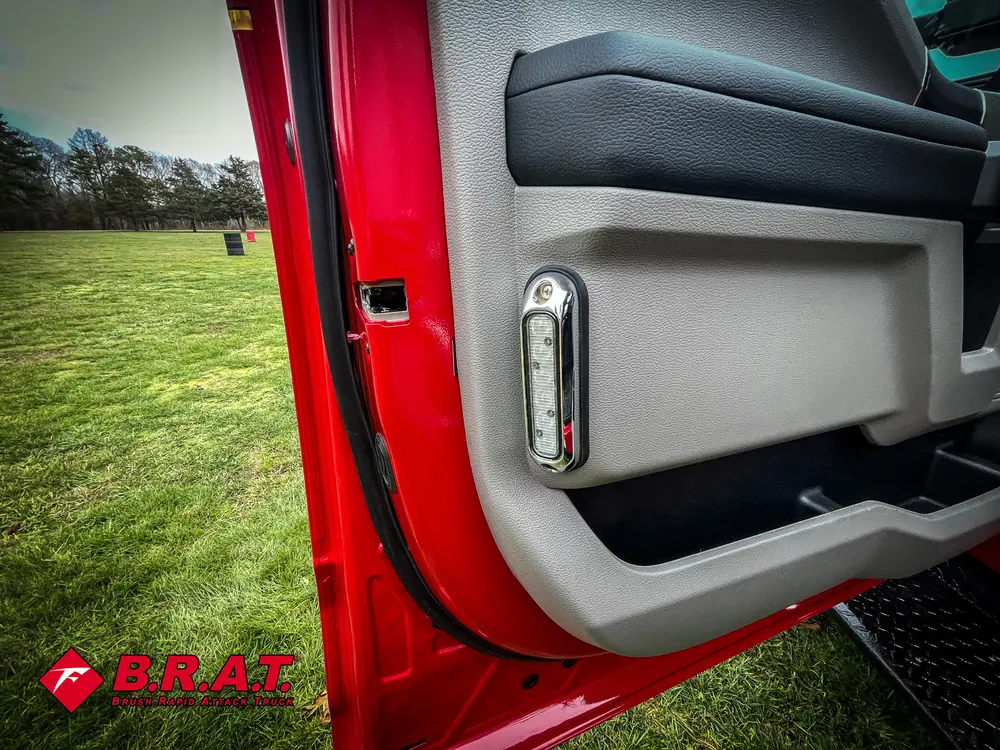 Exterior view of small fire truck showing cab, body compartments, and wheel/tire area.