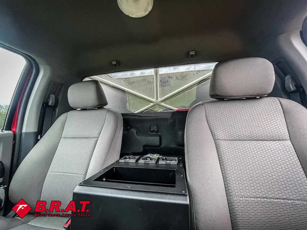 Exterior view of small fire truck showing cab, body compartments, and wheel/tire area.