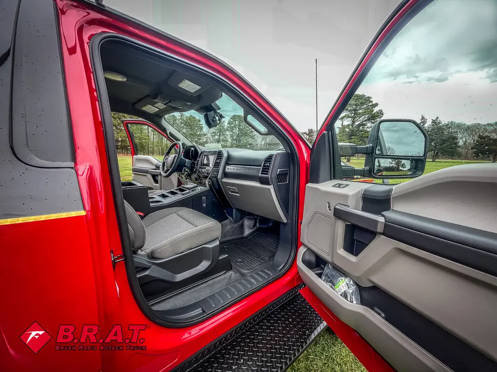 Exterior view of small fire truck showing cab, body compartments, and wheel/tire area.