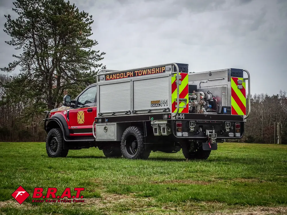 Exterior view of small fire truck showing cab, body compartments, and wheel/tire area.