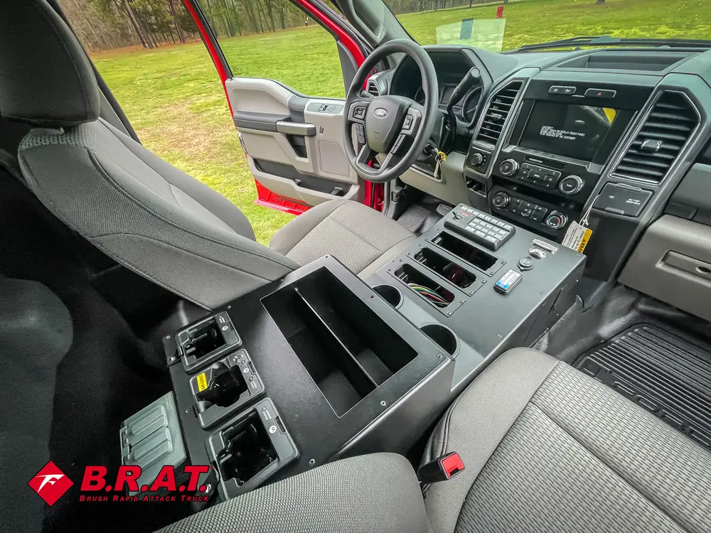 Exterior view of small fire truck showing cab, body compartments, and wheel/tire area.
