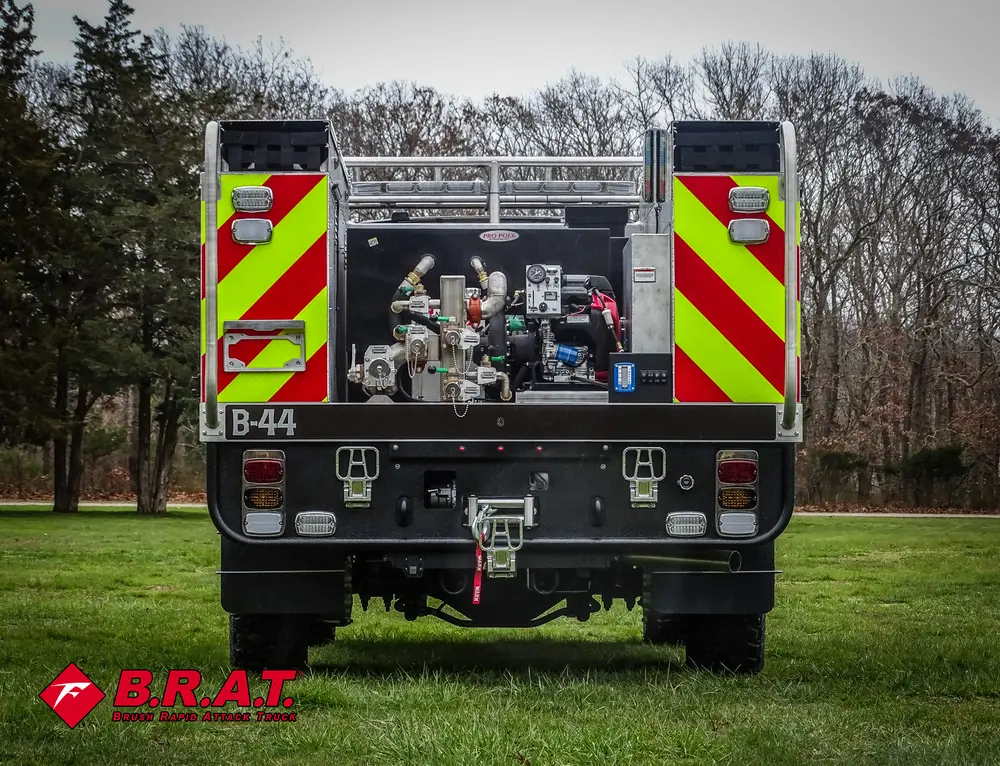 Exterior view of small fire truck showing cab, body compartments, and wheel/tire area.