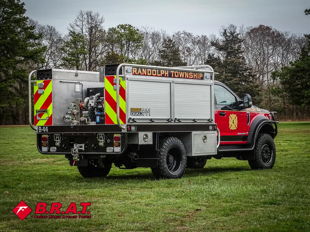 Exterior view of small fire truck showing cab, body compartments, and wheel/tire area.