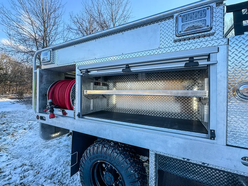 Open side compartment with a red hose reel and shelf above.
