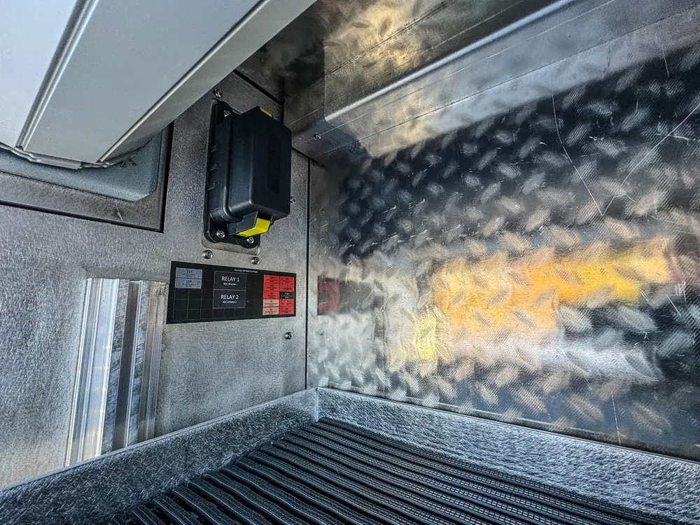 Interior view inside a side compartment showing electrical hardware and wiring.