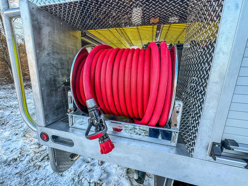 Close-up of a side compartment containing a red hose reel.