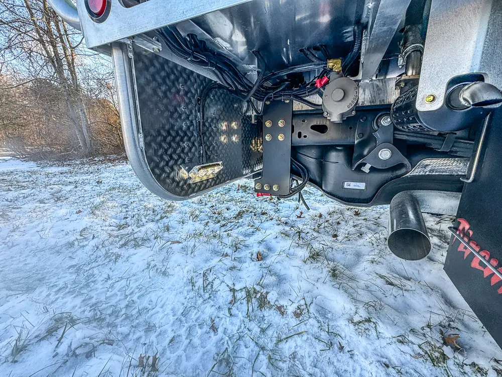 Low rear underside view showing hitch, suspension parts, and exhaust outlet.