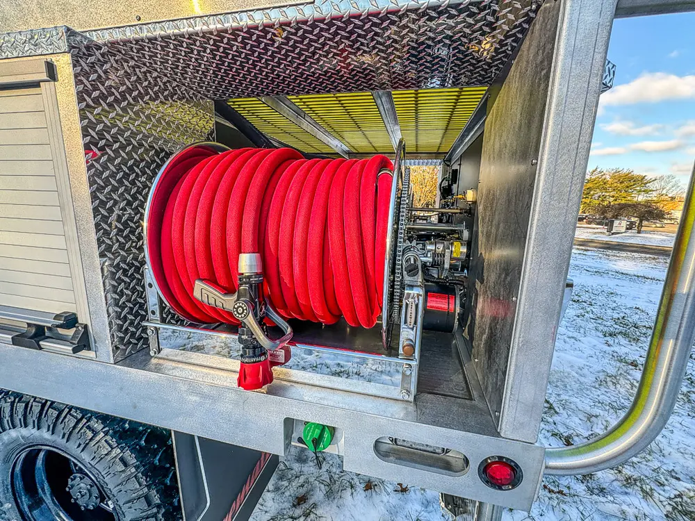 Open side compartment close-up with red hose reel mounted inside.