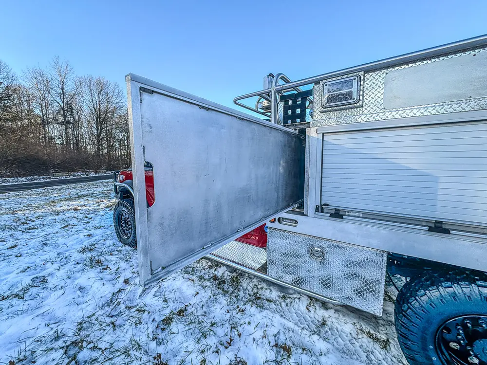 Side view with a long utility-body compartment door fully opened.