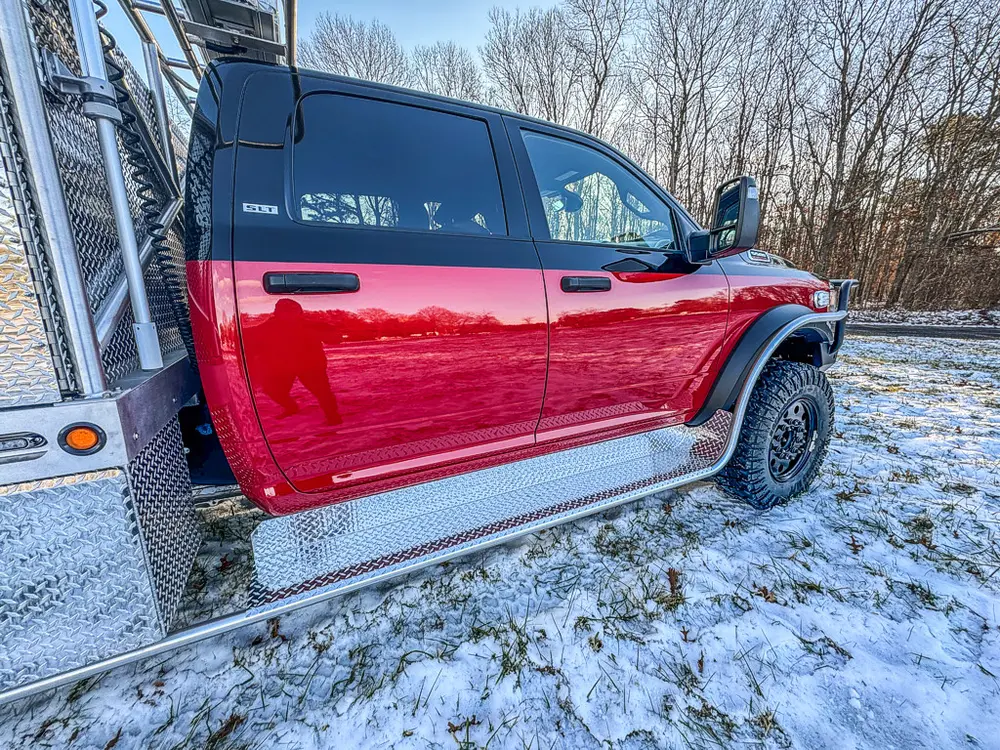 Side view of the red crew cab with utility body behind it.