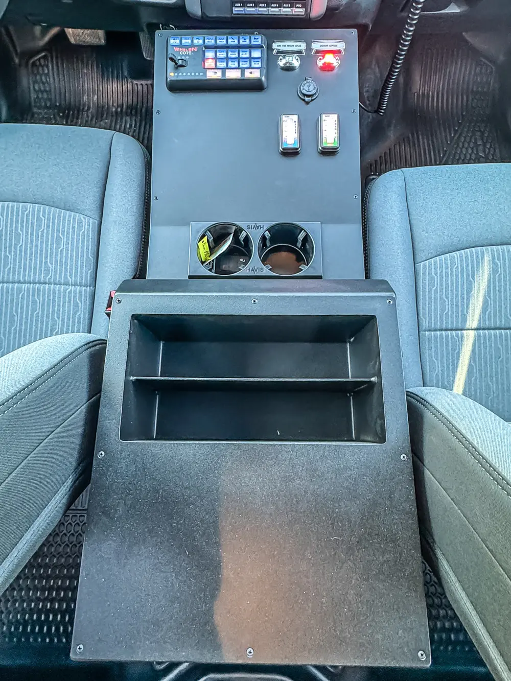 Close-up of rear-facing center console storage and cup holders between front seats.