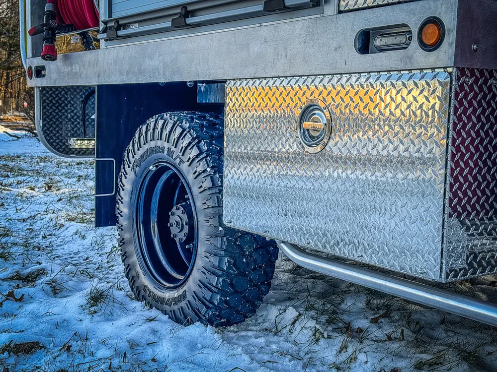 Close-up of rear wheel area and lower diamond-plate utility body panel.