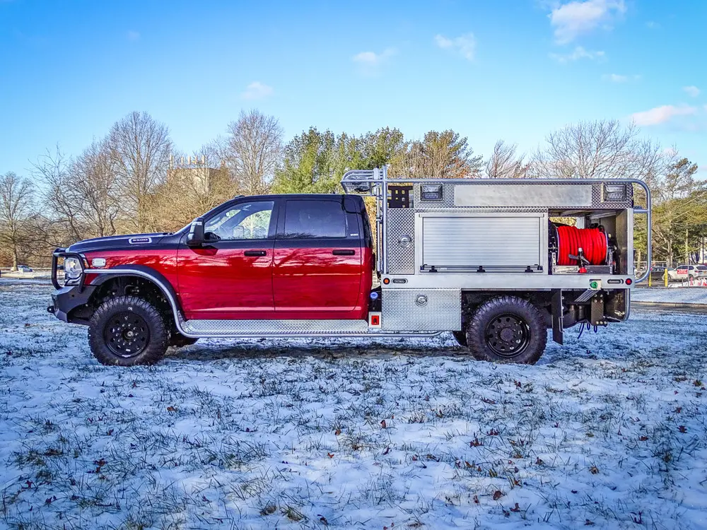 Left-side profile showing the utility body, side compartments, and rear hose reel.