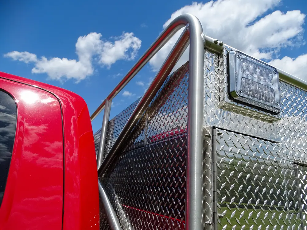 Exterior view of small fire truck showing cab, body compartments, and wheel/tire area.