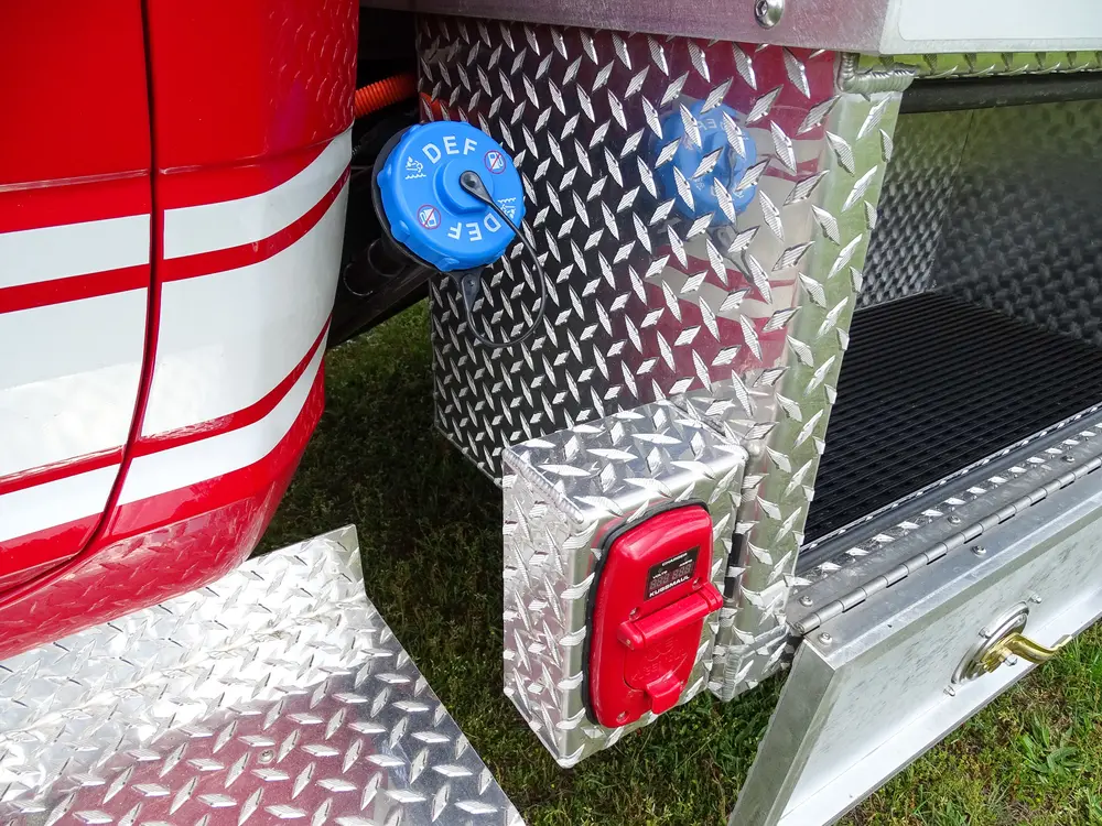 Exterior view of small fire truck showing cab, body compartments, and wheel/tire area.
