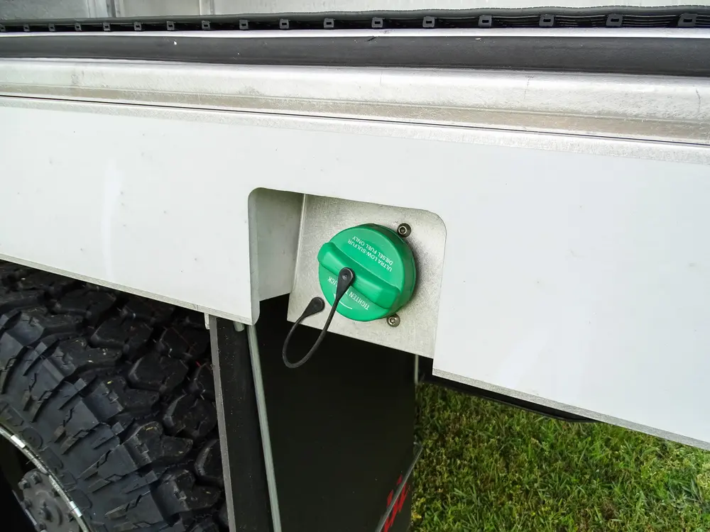 Exterior view of small fire truck showing cab, body compartments, and wheel/tire area.