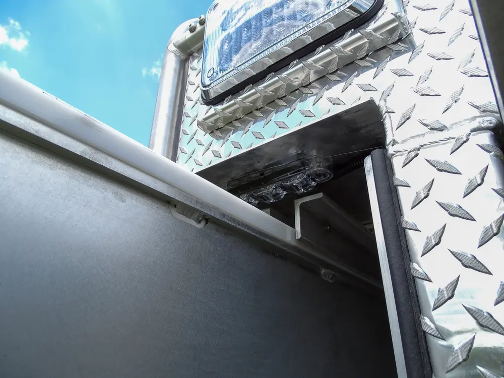 Exterior view of small fire truck showing cab, body compartments, and wheel/tire area.