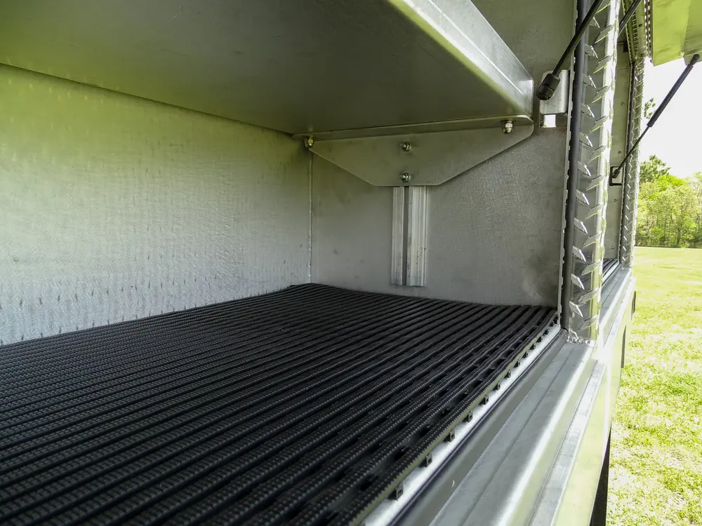 Exterior view of small fire truck showing cab, body compartments, and wheel/tire area.