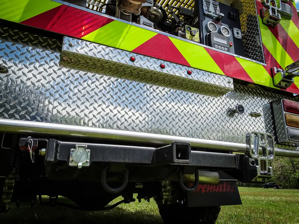 Exterior view of small fire truck showing cab, body compartments, and wheel/tire area.