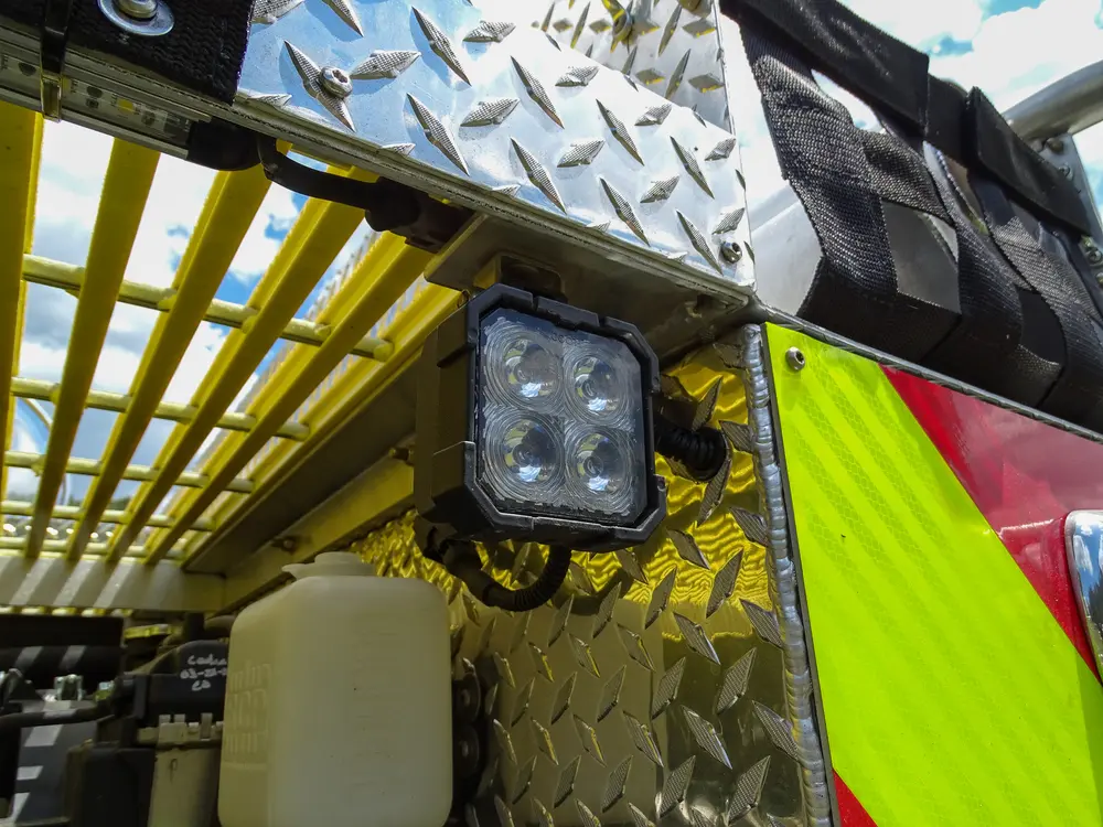 Exterior view of small fire truck showing cab, body compartments, and wheel/tire area.