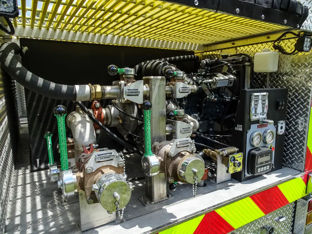 Exterior view of small fire truck showing cab, body compartments, and wheel/tire area.