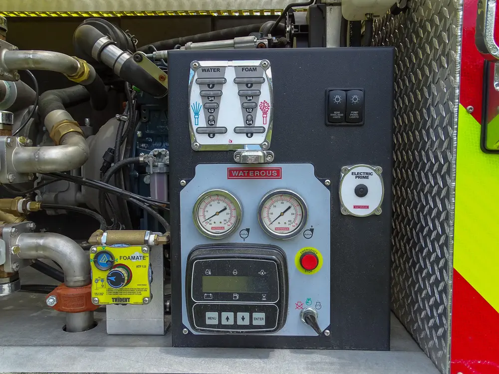 Exterior view of small fire truck showing cab, body compartments, and wheel/tire area.