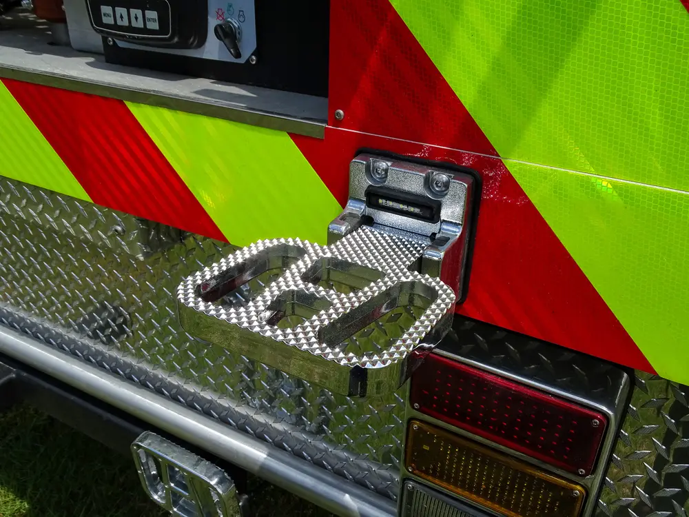 Exterior view of small fire truck showing cab, body compartments, and wheel/tire area.