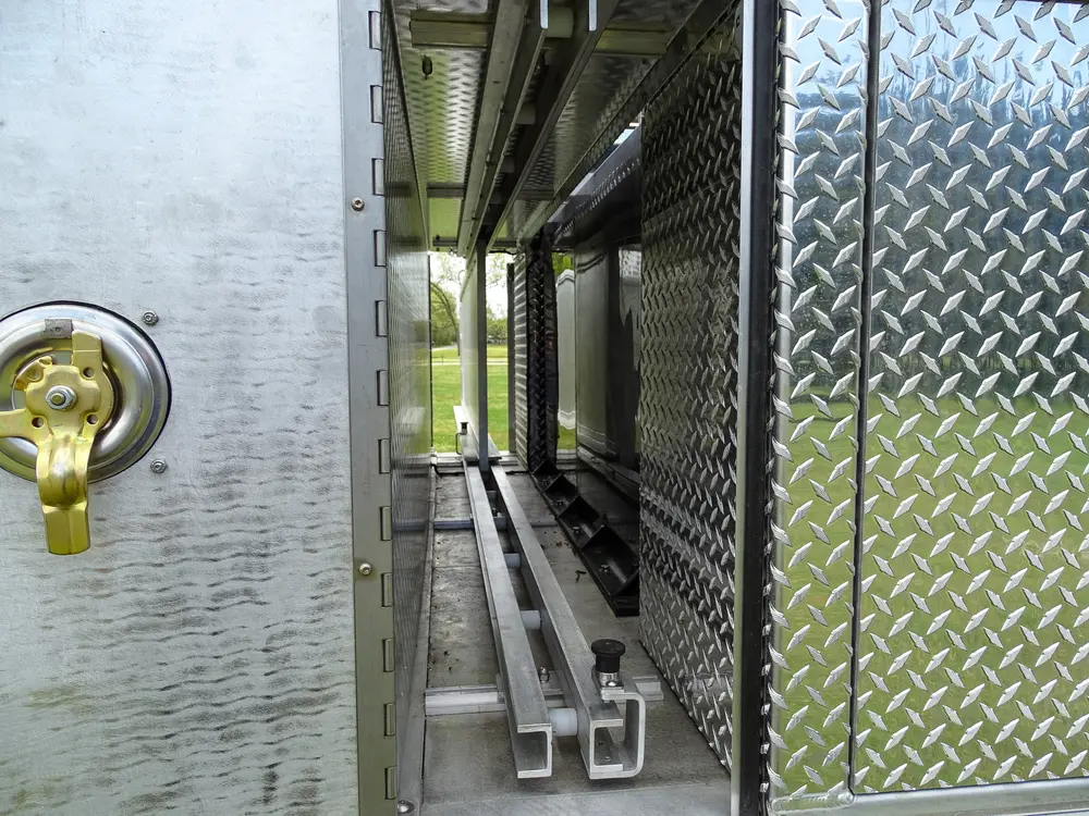 Exterior view of small fire truck showing cab, body compartments, and wheel/tire area.