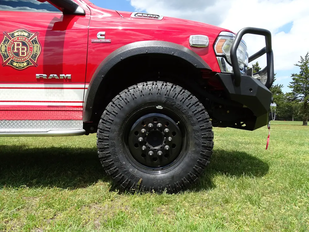 Exterior view of small fire truck showing cab, body compartments, and wheel/tire area.