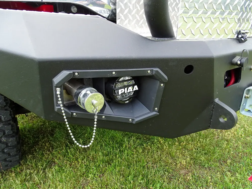 Exterior view of small fire truck showing cab, body compartments, and wheel/tire area.