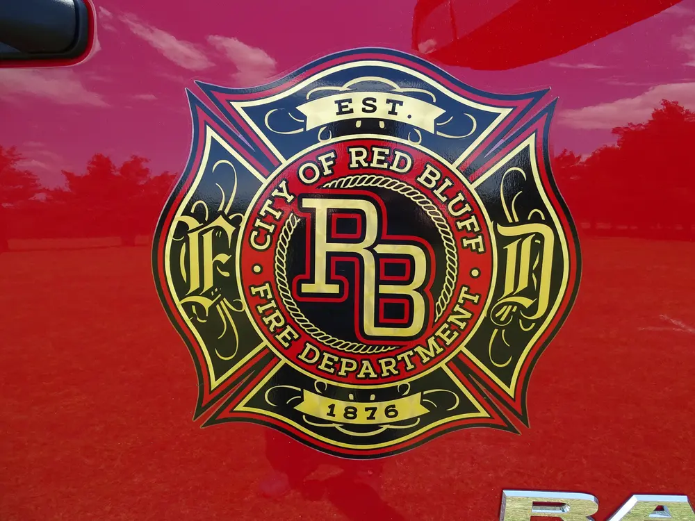 Exterior view of small fire truck showing cab, body compartments, and wheel/tire area.