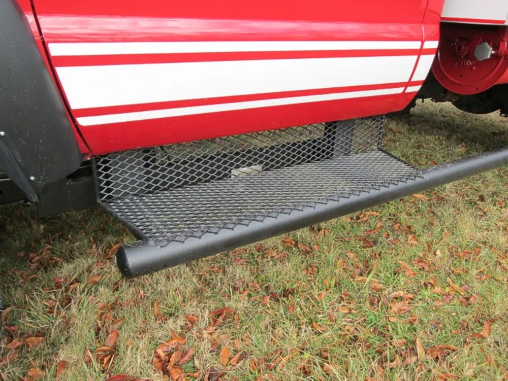 Exterior view of small fire truck showing cab, body compartments, and wheel/tire area.