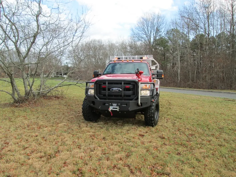 Exterior view of small fire truck showing cab, body compartments, and wheel/tire area.