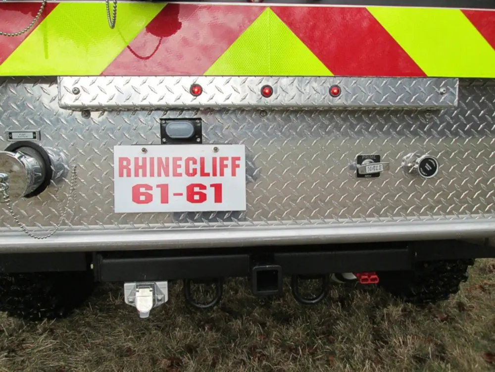 Exterior view of small fire truck showing cab, body compartments, and wheel/tire area.