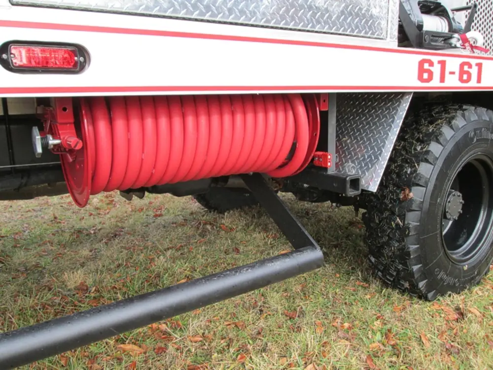 Exterior view of small fire truck showing cab, body compartments, and wheel/tire area.