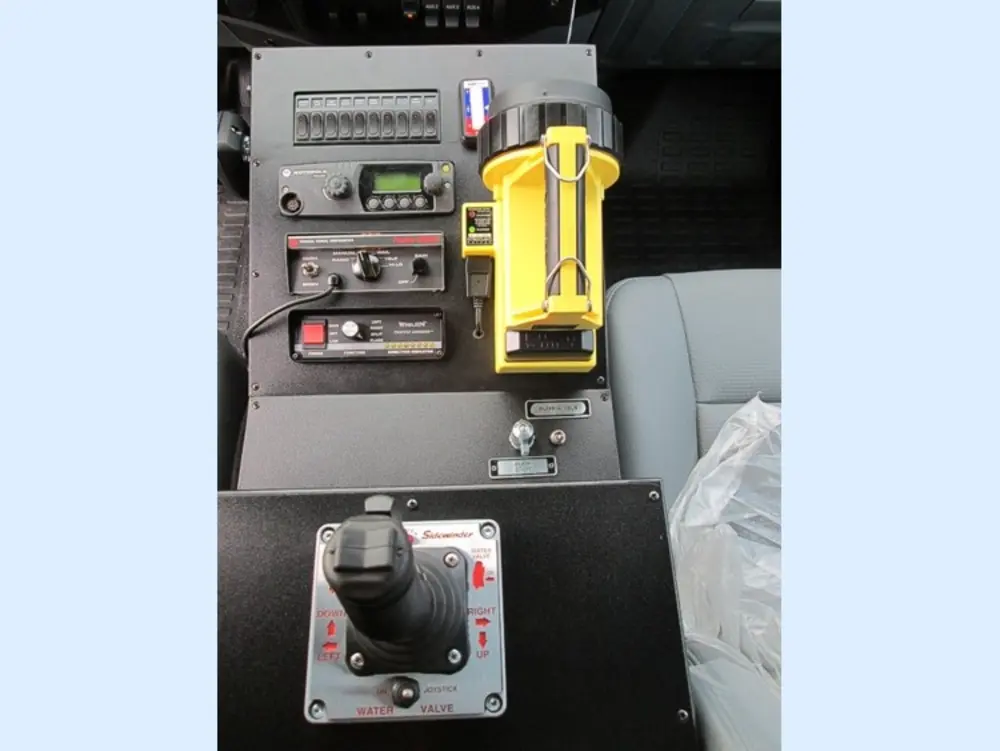 Exterior view of small fire truck showing cab, body compartments, and wheel/tire area.