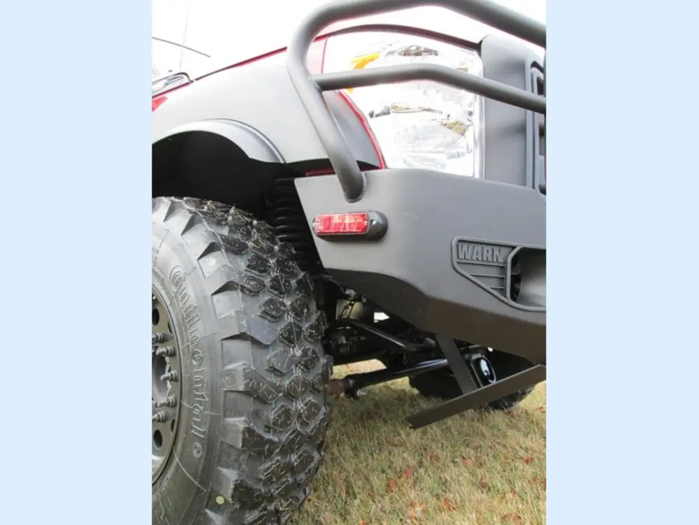 Exterior view of small fire truck showing cab, body compartments, and wheel/tire area.