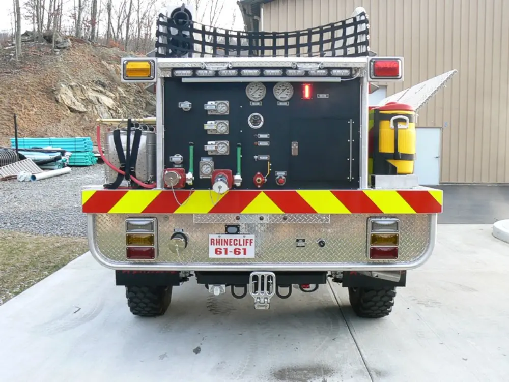 Exterior view of small fire truck showing cab, body compartments, and wheel/tire area.
